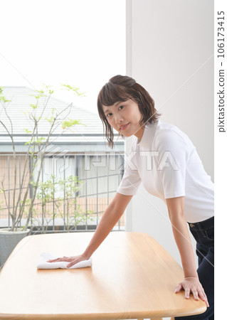 A woman wiping the table with a cloth A woman wiping the table with a cloth 106173415
