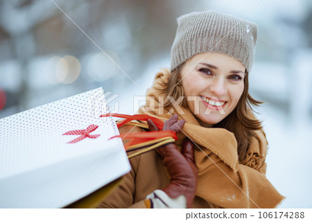 smiling stylish woman in brown hat and scarf in camel coat smiling stylish woman in brown hat and scarf in camel coat 106174288