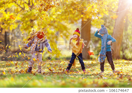 Children playing by throwing leaves to each other in the autumnal natural park. Children playing by throwing leaves to each other in the autumnal natural park. 106174647