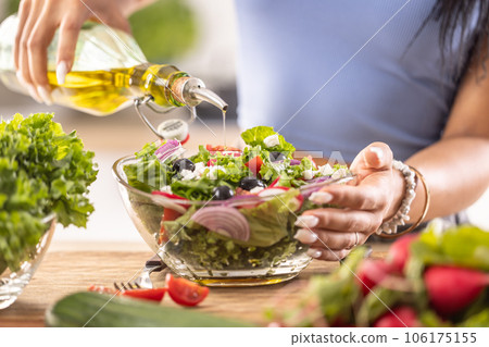 The final preparation of a healthy salad and at the end the woman pours olive oil 106175155