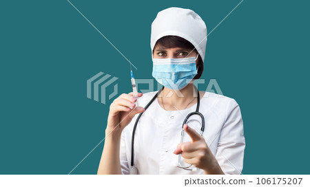 Doctor with a syringe with an injection points his finger at the camera calling for vaccination 106175207