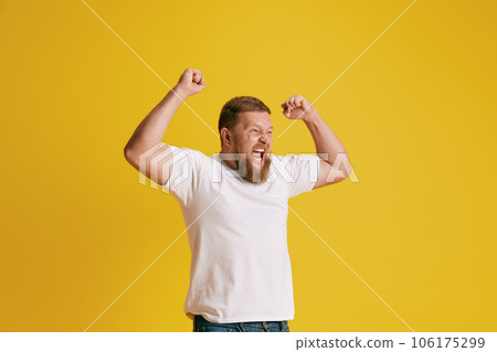 Bearded man, sport fun feeling happy and excited, raising hand up against yellow studio background. Success Bearded man, sport fun feeling happy and excited, raising hand up against yellow studio background. Success 106175299