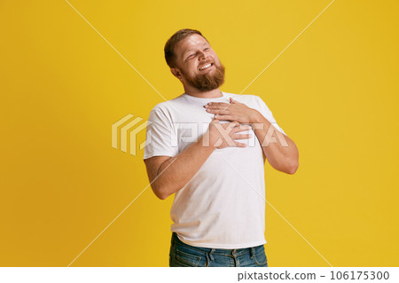 Handsome, smiling, positive bearded man feeling happy and delightful against yellow studio background 106175300