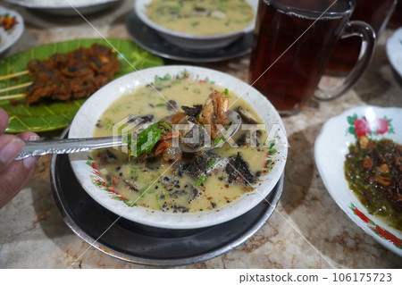 A bowl of Medan style soto or soup with a combination of beef, shrimp, and chicken, along with potato slices in a creamy broth A bowl of Medan style soto or soup with a combination of beef, shrimp, and chicken, along with potato slices in a creamy broth 106175723
