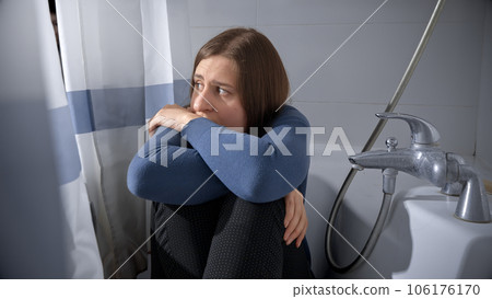 Scared woman being victim of domestic violence and abuse hiding in bath 106176170