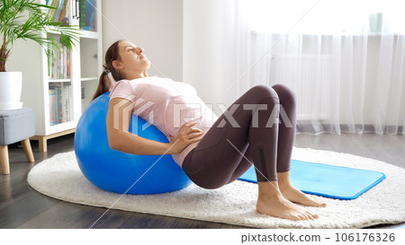 Young woman doing exercises on blue fitball at home. Concept of healthcare, sports and yoga at home. Young woman doing exercises on blue fitball at home. Concept of healthcare, sports and yoga at home. 106176326