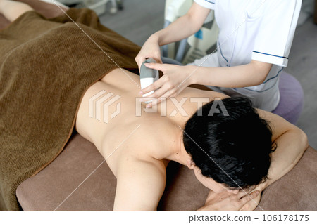 Therapist and male patient performing hair removal treatment on the back Therapist and male patient performing hair removal treatment on the back 106178175