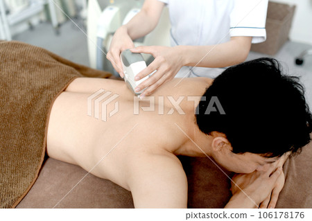 治療師和男性患者進行背部脫毛治療 治療師和男性患者進行背部脫毛治療 106178176