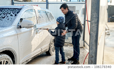 Young father teaching his little son wshing car at self service cash wash Young father teaching his little son wshing car at self service cash wash 106178340