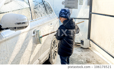Little boy washing car at self-service carwash. Concept of parenting, children helping parents and automobile care. 106178521