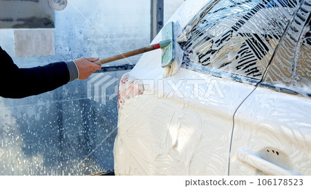 Closeup of man cleaning dirty white car with soft brush on self service car wash Closeup of man cleaning dirty white car with soft brush on self service car wash 106178523