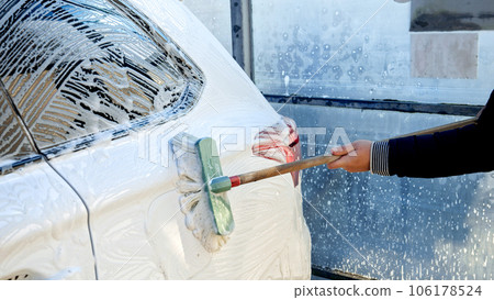 Closeup of washing dirty car with soap foam and brush. Automobile care, transport cleaning, dirty car. Closeup of washing dirty car with soap foam and brush. Automobile care, transport cleaning, dirty car. 106178524