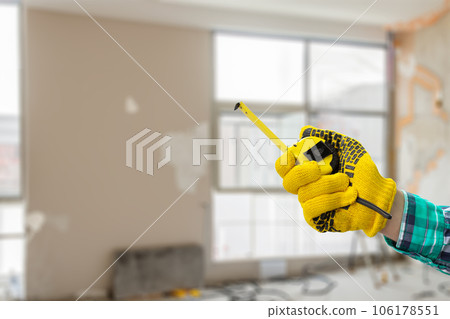 Repairman hand shows a measuring tape. 106178551