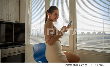 Smiling woman drinking coffee and browsing internet on smartphone at morning. People in morning, beautiful cityscape, having break at office. Smiling woman drinking coffee and browsing internet on smartphone at morning. People in morning, beautiful cityscape, having break at office. 106178608