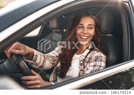 Young smiling woman driving a car in the city 106179314