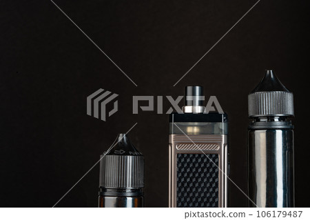 Vape and vape liquid bottles against black background Vape and vape liquid bottles against black background 106179487