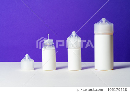 Electronic cigarettes liquid bottles on purple background Electronic cigarettes liquid bottles on purple background 106179518