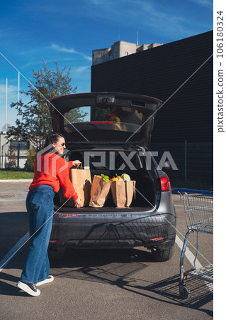 woman put packages in car trunk woman put packages in car trunk 106180324