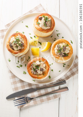 French puff pastry Vol au vent filling with chicken, cream and mushroom closeup on the plate on the wooden table. Vertical top view 106180391