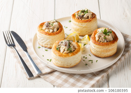 Vol-au-Vent is a hollow puff pastry shell filled with a creamy mushroom and chicken filling closeup on the plate. Horizontal 106180395