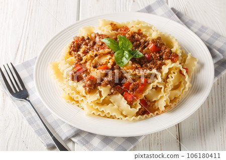 Mafalde or Mafalda or Mafaldine Pasta Bolognese closeup on the plate on the wooden table. Horizontal Mafalde or Mafalda or Mafaldine Pasta Bolognese closeup on the plate on the wooden table. Horizontal 106180411