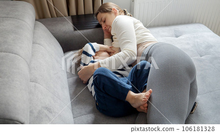 Mother breastfeeds her baby son on the sofa, creating a loving and secure environment for him. Concept of nurturing, maternal care, and the importance of breastfeeding. Mother breastfeeds her baby son on the sofa, creating a loving and secure environment for him. Concept of nurturing, maternal care, and the importance of breastfeeding. 106181328