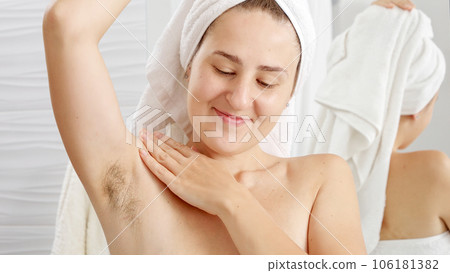 Portrait of smiling natural woman with growing armpit hair posing in bathroom. Concept of hygiene, natural beauty, feminity and body hair growth. 106181382