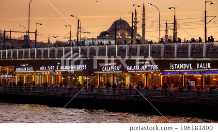 Famous Turkish restaurants and fisherman catching fish on the Galata Bridge at sunset in Istanbul. 15th of March, 2023, Turkey, Istanbul. 106181800