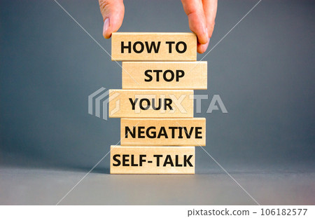 Stop negative self-talk symbol. Concept words How to stop your negative self-talk on wooden block. Psychologist hand. Beautiful grey background. Psychological negative self-talk concept. Copy space Stop negative self-talk symbol. Concept words How to stop your negative self-talk on wooden block. Psychologist hand. Beautiful grey background. Psychological negative self-talk concept. Copy space 106182577