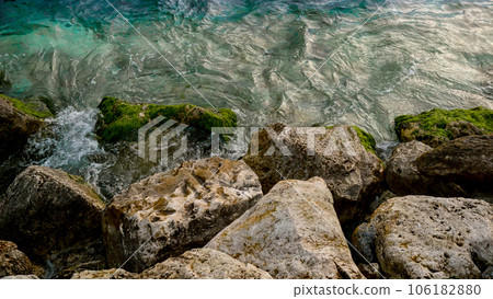 Natural marine backdrop features the beauty of sea waves rolling onto rocky beaches covered with seaweed and algae in slow motion. 106182880