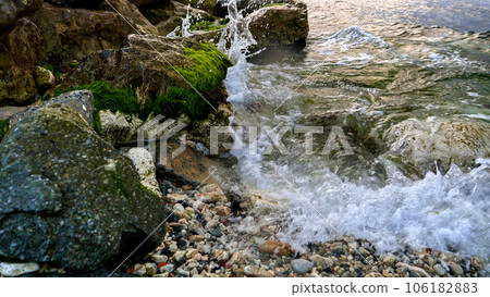Sea waves gently breaking on the rocky beach, adorned with the flourishing seaweeds and algae. Sea waves gently breaking on the rocky beach, adorned with the flourishing seaweeds and algae. 106182883
