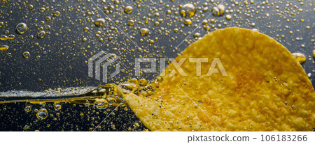 Deep fried potato chips under golden oil water. Frying rounded potatoes chip with hot boiling oil bubbles. Fast food and snack. Underwater cooking oily french fries or potatos chips in oils background 106183266
