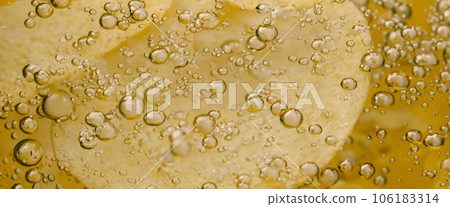 Deep fried potato chips under golden oil water. Frying rounded potatoes chip with hot boiling oil bubbles. Fast food and snack. Underwater cooking oily french fries or potatos chips in oils background 106183314
