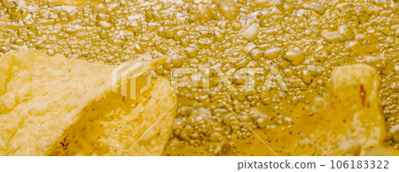 Deep fried potato chips under golden oil water. Frying rounded potatoes chip with hot boiling oil bubbles. Fast food and snack. Underwater cooking oily french fries or potatos chips in oils background 106183322
