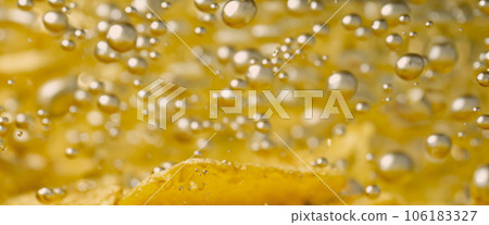 Deep fried potato chips under golden oil water. Frying rounded potatoes chip with hot boiling oil bubbles. Fast food and snack. Underwater cooking oily french fries or potatos chips in oils background 106183327