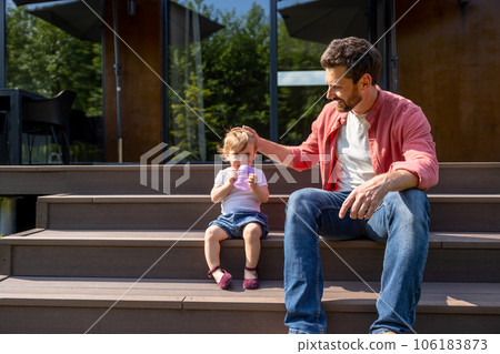 Dad and little son sitting on the steps and looking contented 106183873