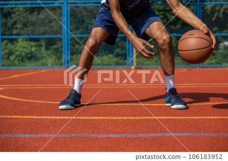 Muscular legs of unrecognizable basketball player training in outdoor court. 106183952