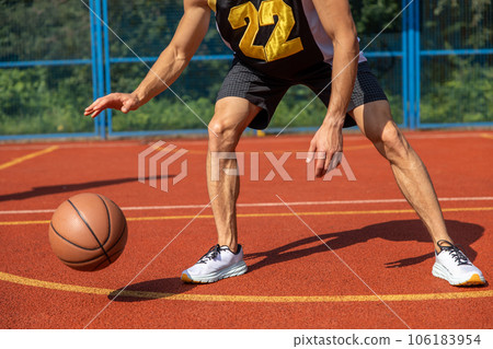 Muscular legs of unrecognizable basketball player training in outdoor court. 106183954
