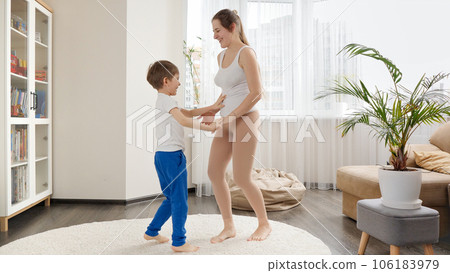 Happy cheerful boy dancing with his mother at home and having fun together. Family having fun together, listening music, active lifestyle, parenting and child development 106183979