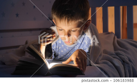 Little boy in pajamas being awake at night reading books with flashlight. Children education, development, secrecy, privacy, reading books. Little boy in pajamas being awake at night reading books with flashlight. Children education, development, secrecy, privacy, reading books. 106183988