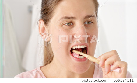 Portrait of brunette woman brushing her perfect white teeth with toothbrush 106184111