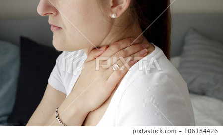 Closeup of young woman massaging her neck feeling pain. Concept of healthcare problems, pain relief and injuries. Closeup of young woman massaging her neck feeling pain. Concept of healthcare problems, pain relief and injuries. 106184426