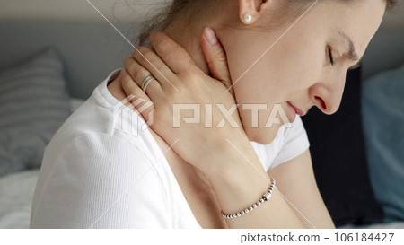 Closeup of young woman massaging her neck feeling pain. Concept of healthcare problems, pain relief and injuries. Closeup of young woman massaging her neck feeling pain. Concept of healthcare problems, pain relief and injuries. 106184427
