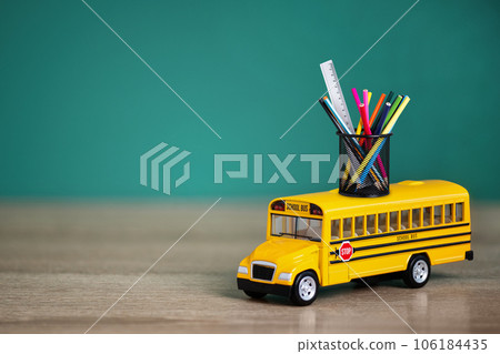 Toy school bus, back to school concept. Creative composition of yellow school bus carrying variety of school supplies. Toy school bus, back to school concept. Creative composition of yellow school bus carrying variety of school supplies. 106184435