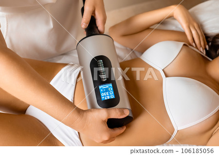 Spa worker massages woman client belly with cellulite remover. Appliance for smoothing skin relief and eliminating flabbiness in adulthood Spa worker massages woman client belly with cellulite remover. Appliance for smoothing skin relief and eliminating flabbiness in adulthood 106185056