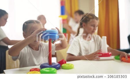 small children play with toys at home. happy family childhood dream concept. a lifestyle group of little kids develops playing with colorful cubes and pyramids. educational games with colored toys 106185303