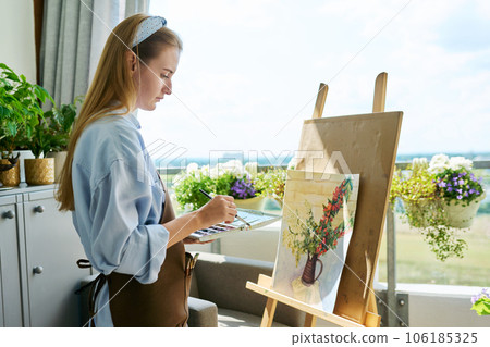 Young teenage female artist painting with watercolors, watercolor painting on easel. Young teenage female artist painting with watercolors, watercolor painting on easel. 106185325