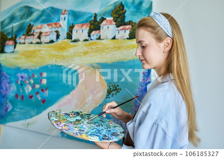 Young woman artist painting picture on canvas on wall Young woman artist painting picture on canvas on wall 106185327