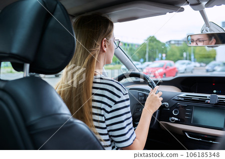 Teenage girl driver in glasses sitting behind wheel of car Teenage girl driver in glasses sitting behind wheel of car 106185348