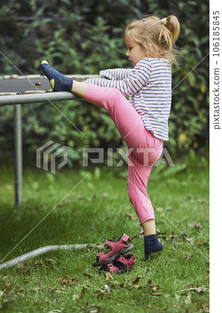 Curious child climbs on a trampoline in the evening garden in Denmark 106185845